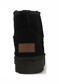 Zwarte suède enkellaars met een gestructureerde achterkant, rubberen zool en een bruine leren merklabel. Voorzien van een elastische paneel voor gemakkelijk aan- en uittrekken.