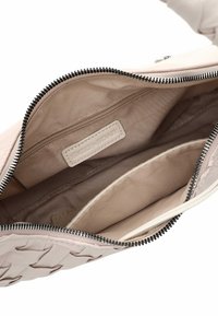 Geweven blush leren tasinterieur, met een beige voering, een ritsvak en een gegraveerd label. Glad materiaal met contrasterende ritsdetails.