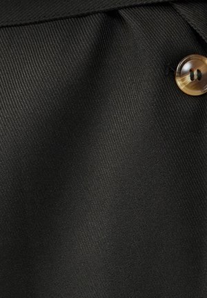 Zwarte stof met een gestructureerde textuur en verticale ribbels, met een enkele ronde, lichtbruine knop als opvallend detail.