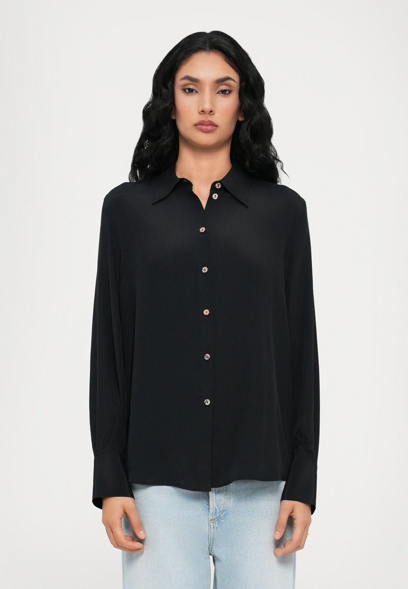 Camisa preta de manga longa abotoada com colarinho pontudo, textura suave e botões decorativos com um padrão de cor subtil.
