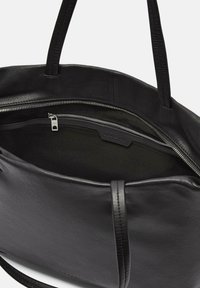 Zwarte leren tote bag met dubbele handvatten, voorzien van een ritssluiting en een ruime binnenkant met een gevoerd vak en merkdetails.