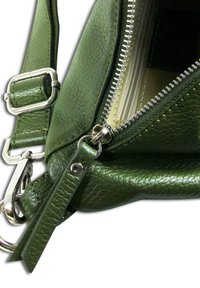 Sac à main en cuir vert avec une finition texturée, doté d'une fermeture à glissière en argent, d'une sangle ajustable et d'accents en métal.