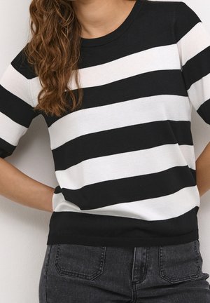 Pull en maille à rayures noires et blanches avec des manches courtes, un col rond et un ourlet noir uni, associé à un jean foncé.