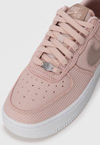 Sapatilha texturizada rosa com material ribbed, sola de borracha branca e detalhe em logótipo prateado. Apresenta design com atacadores e biqueira perfurada para ventilação.