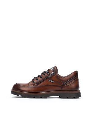 Zapatos de cuero marrón con una textura suave, diseño con cordones y una cremallera lateral. Suela de goma ligera con un agarre texturizado.