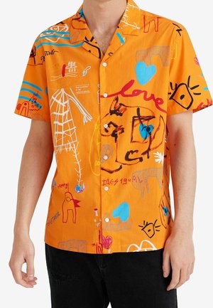 Leuchtend orangefarbenes Kurzarmhemd mit bunten abstrakten Kritzeleien, Herzen, Gesichtern und dem Wort "Liebe" in roter Schreibschrift, getragen zu schwarzer Hose.