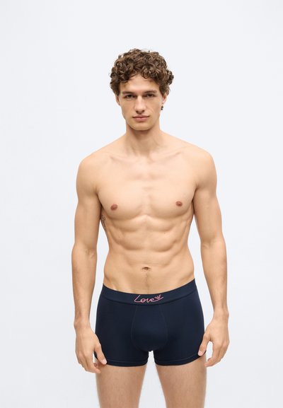 Tengerészkék boxeralsó, testhez simuló kialakítással, rózsaszín "Love" logóval a derékrészen, sima, rugalmas anyaggal.