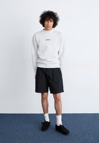 Gray sweatshirt with "Service" text, black shorts, white socks, and black shoes. Simple design with a relaxed fit and smooth texture.
