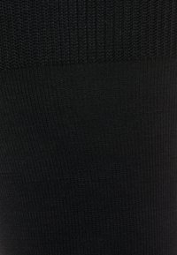 Sorte strikkede sokker med en ribbet øverste sektion og glat, ensartet tekstur hele vejen igennem. Det overordnede design er enkelt og monokromatisk.