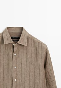 Chemise beige à manches longues avec boutons et fines rayures verticales, dotée d'un col pointu, fabriquée en tissu 100 % lin.