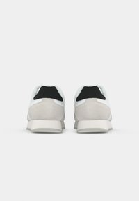 Een paar witte en lichtgrijze sneakers met zwarte hieltabs, gezien van achteren op een effen witte achtergrond.