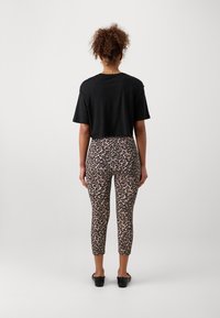 Black cropped t-shirt paired with leopard print leggings. The leggings feature a fitted design and mid-calf cut. Smooth fabric texture.