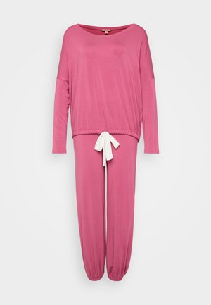 Ensemble de loungewear rose comprenant un haut à manches longues et un pantalon fuselé. La taille est dotée d'un cordon blanc, fabriqué dans un tissu doux et lisse.