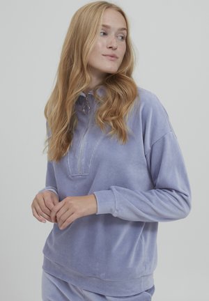Lilla pullover sweatshirt i blødt, plyssende stof. Har en kvart lynlås, høj krave og ribbede manchetter, med en afslappet pasform og minimal syning.