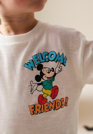 Fehér pamut póló, színes, nyomtatott rajzfilmfigurával és a "WELCOME FRIENDS!" felirattal vastag betűkkel.