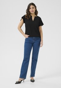 Black short-sleeve top with a V-neck is paired with blue straight-leg jeans. The shoes are pointed-toe black pumps with a decorative buckle.