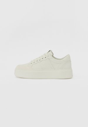 White leather sneaker with a textured toe, flat laces, and a thick platform sole. Minimalist design with subtle stitching details.