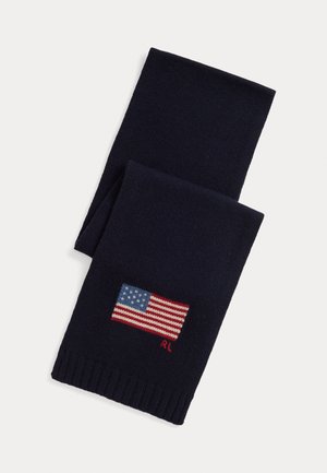 Tumes sinine kudumismüts ribidega äärtega, millel on väike tikand Ameerika lipp ja "RL" logo punasena, luues tekstuurse viimistluse.