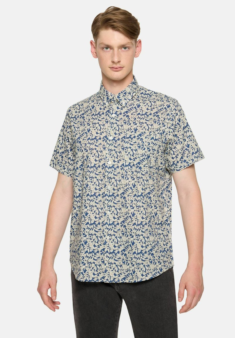 Camisa de manga corta con botones que presenta un patrón floral en crema y azul marino sobre una tela ligera. Dobladillo recto y cuello puntiagudo.