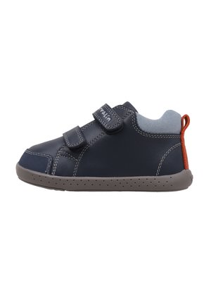 Zapato de cuero azul marino con acentos de textil gris, doble correa de velcro y suela de goma gris con perforaciones y una lengüeta roja en el talón.