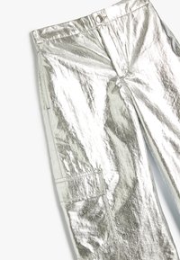 Sølvmetallic cargo bukser med en skinnende, reflekterende tekstur, der har en knaplukning og sidelommer. Flad front og lige skæring.