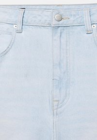 Jean en denim bleu clair avec fermeture à boutons sur le devant, passants de ceinture et coutures visibles.