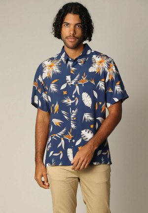 Chemise à manches courtes, bleu marine avec des boutons, ornée d'un motif floral tropical en blanc et orange. Design avec col, tissu léger, coupe décontractée.