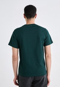 Dark green cotton t-shirt with a crew neckline and short sleeves. Smooth texture, simple design, no visible patterns or accents.