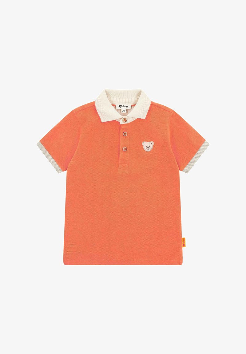 Koronkowa koszulka polo w kolorze koralowym z teksturowanym wykończeniem, białym kołnierzykiem, haftem misia na klatce piersiowej i paskowanymi akcentami na rękawach. Zapięcie na trzy guziki.