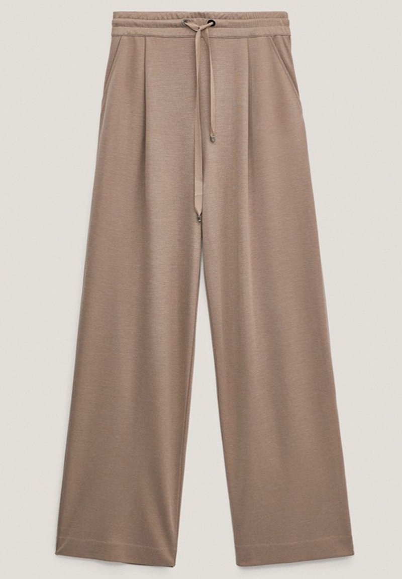 Pantalon beige ample à jambes larges avec taille élastique et cordon de serrage, doté de poches latérales et d'une texture de tissu lisse.
