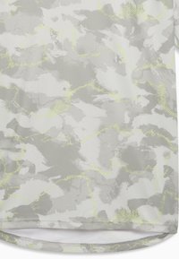 Ύφασμα παραλλαγής σε γκρι και λευκό με διακριτικές κίτρινες γραμμές και ορατή ραφή πουκάμισου στο κάτω  μέρος, που δείχνει ένα υφασμένο μοτίβο.