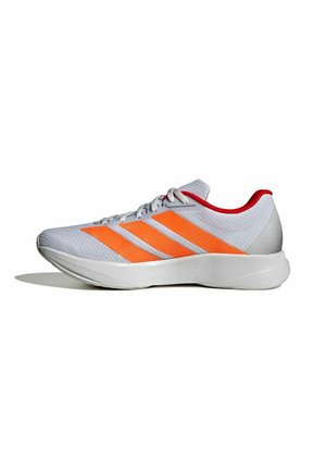 Scarpa sportiva grigio chiaro con strisce arancioni, suola bianca, chiusura con lacci e rivestimento interno rosso, mostrata di profilo su sfondo bianco.