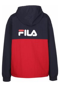 Giacca a vento rossa e blu navy, con un grande logo FILA bianco sulla schiena, bordi elastici e una texture di tessuto leggero.