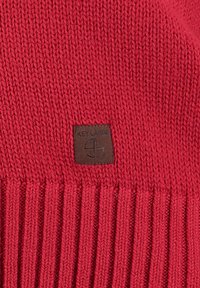 Berretto rosso lavorato a maglia con un motivo testurizzato, bordi a costine e una toppa marrone con la scritta "KEY LARGO."
