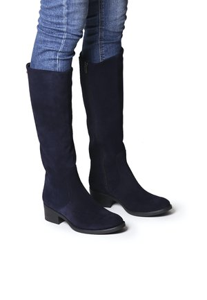 Bottes montantes en daim bleu marine avec un talon plat et une fermeture éclair sur le côté, présentant une texture lisse et un design à bout arrondi.