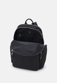 Sac à dos noir avec une surface textile lisse, une forme arrondie, des compartiments zippés et un intérieur doté d'une doublure à motif.