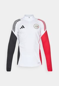 Hvid atletisk pullover med sorte og røde accenter, har en kvart lynlås krave, lange ærmer og et cirkulært logo på brystet.