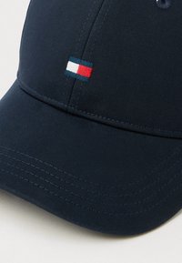 Tengerészeti baseball sapka texturált anyagból, ívelt karimával. Kicsi, piros, fehér és kék színű, hímezett téglalap alakú logó található rajta.