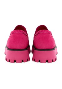 Rosa Wildleder Slipper mit dicken Gummisohlen, die einen gezackten Rand und eine abgerundete Ferse aufweisen, von hinten betrachtet.