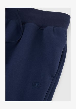 Pantalones de chándal azul marino hechos de tela suave, con cintura elástica, cordón y un pequeño logotipo en el muslo izquierdo.