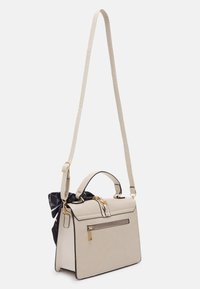 Beige handväska med en strukturerad design, svart sjal som accent, texturerad yta, guldfärgade detaljer, ovandelshandtag och justerbar axelrem.