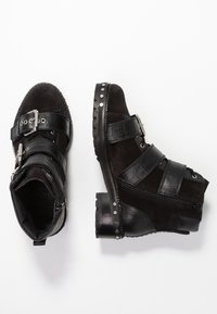 Botas negras de tobillo hechas de ante y material sintético, con acentos de patrón de cocodrilo, dos correas ajustables y detalles de remaches en la suela.