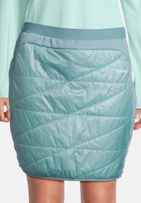 Falda acolchada en color teal con costuras acolchadas diagonales, cintura elástica y marca Schöffel. Fabricada con un tejido ligero y resistente al agua.