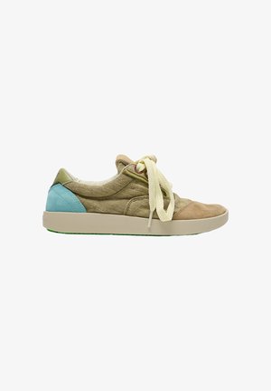 Zapatilla casual de perfil bajo con parte superior de tela beige, cordones crema, parche azul claro en el talón y suela de goma beige.