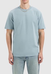 Lichtblauw katoenen t-shirt met korte mouwen, een ronde hals en een relaxed fit, met een klein logo op de onderzijde rechts.