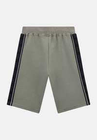 Vihreät puuvillashortsit, joissa on leveä elastinen vyötärö, mustat sivupaneelit toistuvalla kuviolla ja valkoiset saumat.