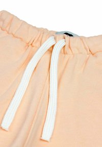 Helle Pfirsichfarbene Shorts mit Kordelzug aus glatt verarbeitetem Material, ausgestattet mit weißen Kordelzügen und einem elastischen Bund, die lässige Designdetails präsentieren.
