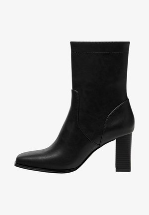 Bottine noire en cuir synthétique lisse avec un bout pointu et un talon bloc côtelé. Présente des coutures minimales et des découpes sur les côtés.