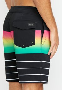 Shorts de bain noirs avec un dégradé de rose, jaune et vert sur la taille. Comprend une poche arrière avec un rabat et un logo.