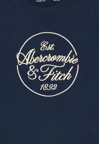 Navy T-shirt with a classic fit, featuring white embroidered text: "Est. Abercrombie & Fitch 1892" encircled. Smooth cotton texture.